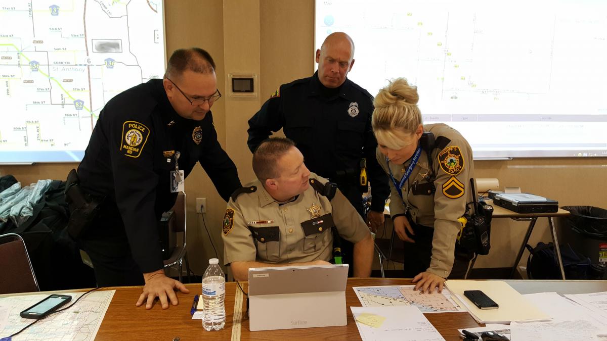 NSA Board of Directors Sheriff Paul Laney from Cass County, seated, discusses current operations with Mandan Police Chief Jason Ziegler, Wisconsin State Highway Trooper Lt. Richard Reichenberger, and Cass County Deputy Tonya Jahner